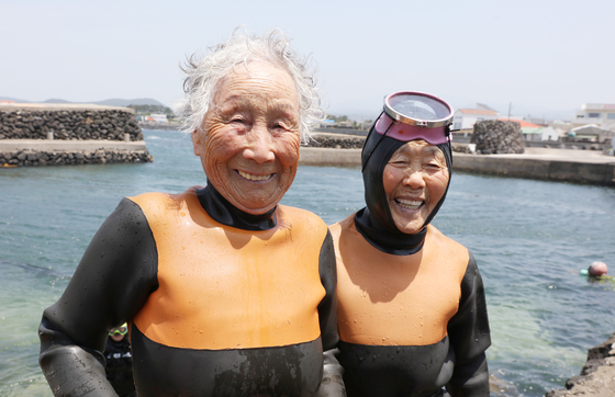 Retiring haenyeo, or female divers, Kim Yoo-sang, left, and Kang Doo-gyo smile for a photo after their final dive last Saturday, which took place before the retirement ceremony began later in the day. [YONHAP]