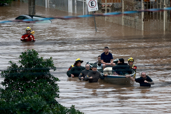 Rescue workers evacuate people from a flooded area at Cavalhada neighborhood after heavy rains in Porto Alegre, May 23. [REUTERS/YONHAP]