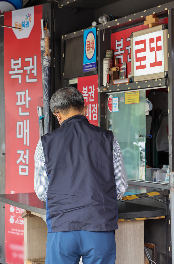 A man purchases a lottery ticket from a lottery store in downtown Seoul on Thursday. [YONHAP]
