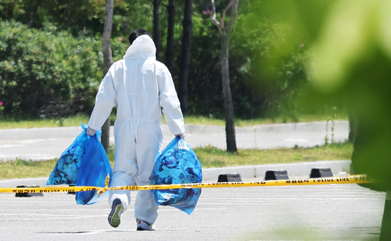 A South Korean worker dressed in a hazmat suit cleans up trash sent over the border by North Korea that landed in a parking lot of a shopping mall in Siheung, Gyeonggi, on Sunday. [YONHAP]