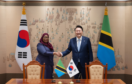 President Yoon Suk Yeol, right, shakes hands with Tanzanian President Samia Suluhu Hassan ahead of their bilateral summit at the Yongsan presidential office in central Seoul on Sunday. [PRESIDENTIAL OFFICE]