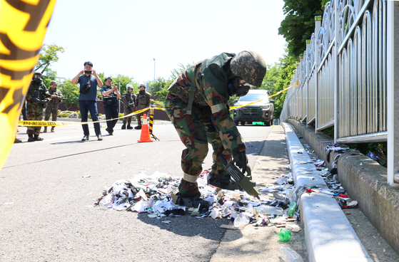 A South Korean soldier uses a chemical testing device to inspect trash strewn across the ground near a weather observatory in Incheon's Jung District on Sunday morning after a balloon sent over the border by the North landed there. [YONHAP]