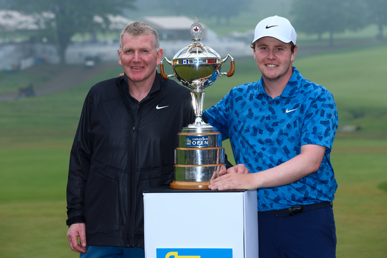 Robert MacIntyre, right, poses with the trophy alongside his caddie and father Dougie MacIntyre after winning the RBC Canadian Open at Hamilton Golf & Country Club in Hamilton, Ontario, Canada on Sunday. [GETTY IMAGES]