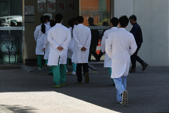 Several medical professionals walk toward a building of a general hospital in Seoul on Tuesday. [YONHAP] 