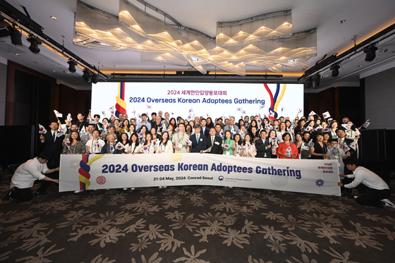 The participants of the Overseas Korean Adoptees Gathering and Lee Key-cheol, commissioner of the Overseas Korean Agency (OKA), center, pose for a photo during the opening ceremony of the event at Conrad Seoul in Yeouido, western Seoul, on Tuesday. [OVERSEAS KOREAN AGENCY]