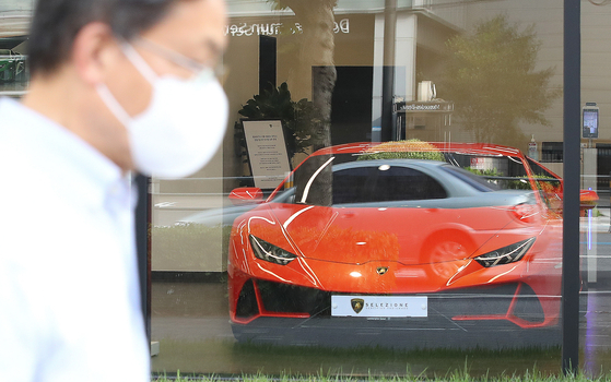 A passerby walks in front of an Automobili Lamborghini dealership in downtown Seoul. [NEWS1]