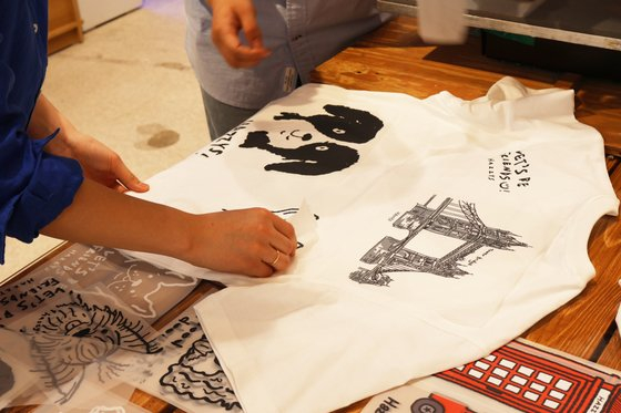 People customize their one-of-a-kind T-shirts at the Hazzys flagship store in Myeong-dong, central Seoul. [LF]