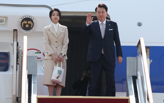 President Yoon Suk Yeol, right, accompanied by first lady Kim Keon Hee, waves Monday morning at Seoul Air Base in Seongnam, Gyeonggi, before heading for state visits to Turkmenistan, Kazakhstan and Uzbekistan. [JOINT PRESS CORPS]