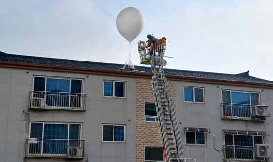 Firefighters respond to a balloon found on the roof of a residential complex in Incheon on Sunday. [INCHEON FIRE SERVICES] 