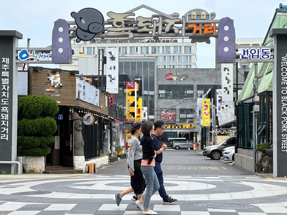 People pass by the Geonip-dong Black Pork Street in Jeju City around noon on June 3. [JOONGANG ILBO] 
