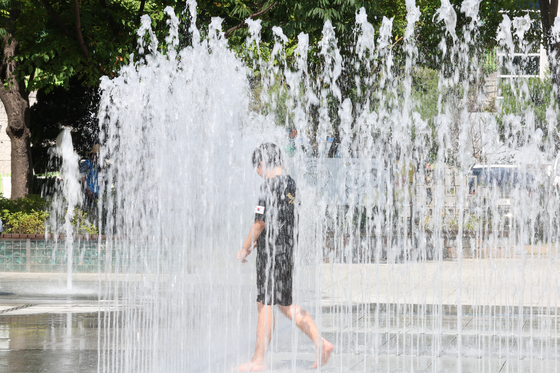 A child enjoy water splashes from a fountain in Daegu on Monday. The daily highest in Daegu on Monday was 33.4 degrees Celsius (91.2 degrees Fahrenheit). [YONHAP]  