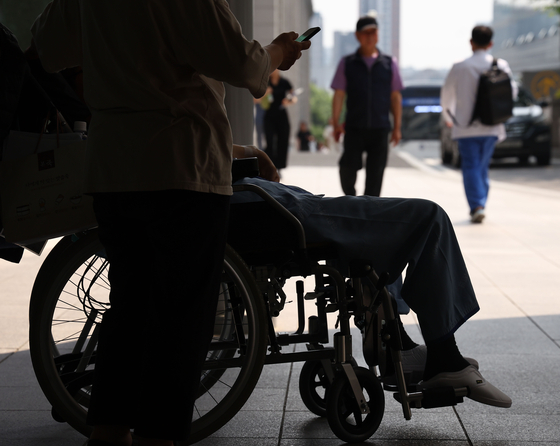 A patient sits in a wheelchair in front of a hospital in Seoul on Wednesday. [YONHAP]