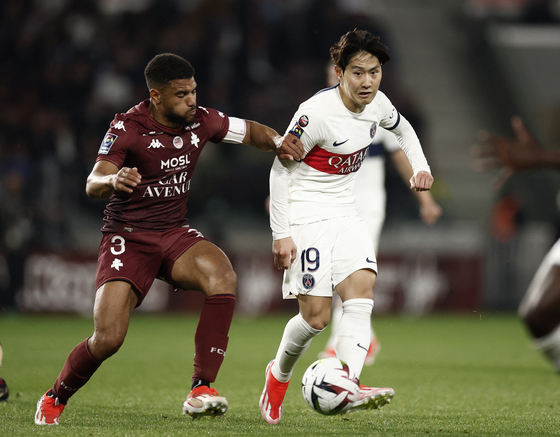 Paris Saint-Germain midfielder Lee Kang-in, right, vies for the ball with Matthieu Udol during a Ligue 1 match against Metz at Stade Saint-Symphorien in Metz, France on May 19. [REUTERS/YONHAP] 