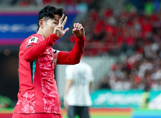 Korea captain Son Heung-min holds up a 3-0 gesture with his hands toward fans after being booed during the first half of a 2026 World Cup qualifying match against China at Seoul World Cup Stadium in western Seoul on Tuesday. [YONHAP]