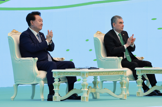 Korean President Yoon Suk Yeol, left, and former Turkmen President Gurbanguly Berdimuhamedow, father of the current president and chairman of the People's Council, clap during a bilateral business forum in Ashgabat, Turkmenistan, on Tuesday. [JOINT PRESS CORPS]