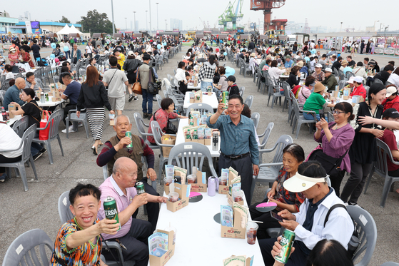 Tourists enjoy free beer and dakgangjeong (glazed chicken nuggets) during the 1883 McGang Party at Sangsang Platform in Jung District, Incheon, on May 25. [NEWS1]