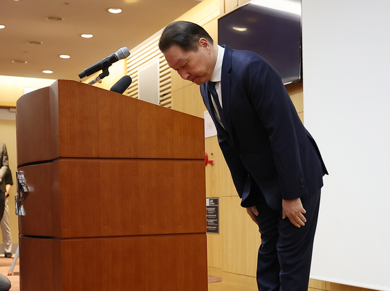 SK Group Chairman Chey Tae-won bows in apology before the press on Monday in central Seoul. [YONHAP]