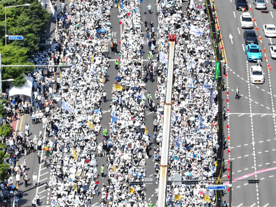 Medical professors, junior doctors, medical students and private practitioners participate in an outdoor rally in Yeouido, western Seoul, on Tuesday, demanding that the government amend its medical policy packages. Over 12,000 health care professionals joined the protest, according to the police. [YONHAP]