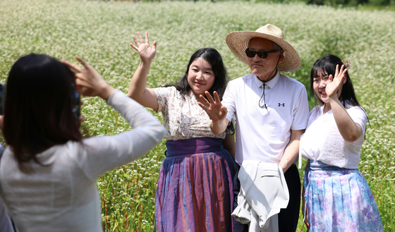 Culture Minster Yu, middle, takes pictures with tourists among buckwheat flowers in Menge Village, Andong, on Wednesday. [MINISTRY OF CULTURE, SPORTS AND TOURISM]