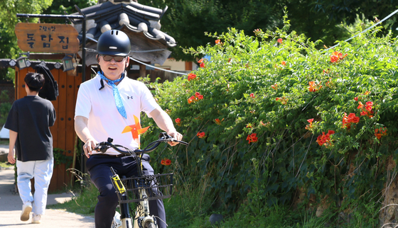 Culture Minister Yu In-chon bikes around hanok (traditional houses) at Otgol Village in Daegu on Wednesday. [MINISTRY OF CULTURE, SPORTS AND TOURISM]