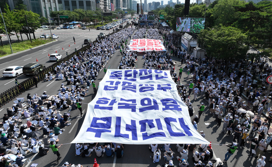 Doctors protest against the government’s medical reform policies on the roads in western Seoul on Tuesday. [YONHAP]