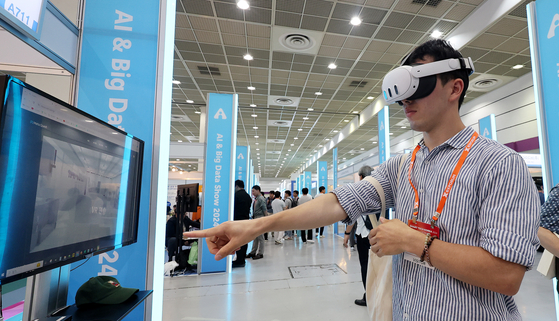 A visitor tries a virtual reality headset displaying a semiconductor production site at Smart Tech Korea 2024 held at Coex in southern Seoul on Wednesday. [NEWS1]