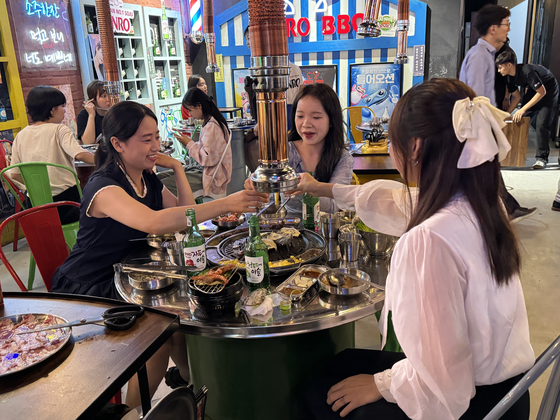 Tham, a 21-year-old Vietnamese, far right, celebrates her friend’s birthday with fruit-flavored soju and samgyeopsal (pork belly) at a restaurant in Hanoi on June 10. [JOINT PRESS CORPS]