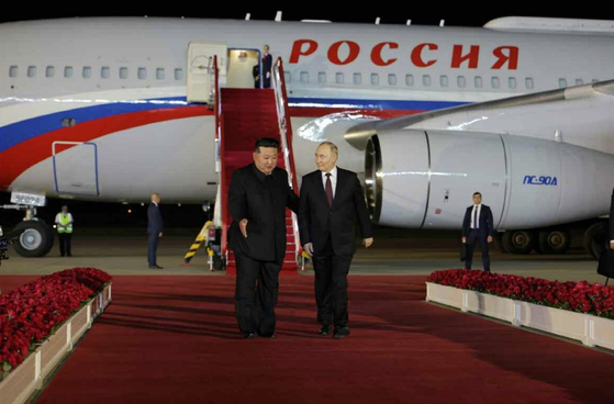 North Korean leader Kim Jong-un, left, gives Vladimir Putin a red-carpet welcome as the Russian leader arrives on his presidential jet at Sunan airport in Pyongyang early Wednesday for a state visit in a photo carried by the North’s official Rodong Sinmun. [NEWS1]