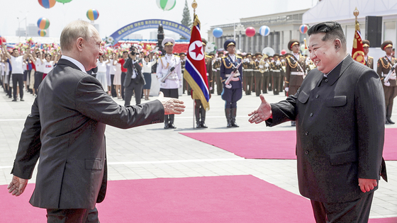 Russian President Vladimir Putin, left, and North Korean leader Kim Jong-un, right, walk to each other to shake hands during an official welcome ceremony in the Kim Il Sung Square in Pyongyang ahead of their bilateral summit on Wednesday. [AP/YONHAP]