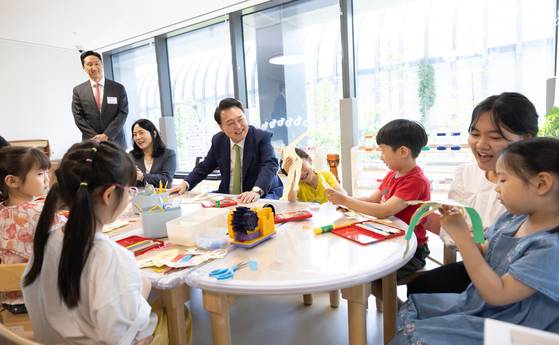 President Yoon Suk Yeol, center, greets children at a day care run by the HD Hyundai Global R&D Center in Seongnam, Gyeonggi, Wednesday, ahead of a meeting of the presidential committee tackling low birthrates and an aging population. [PRESIDENTIAL OFFICE]
