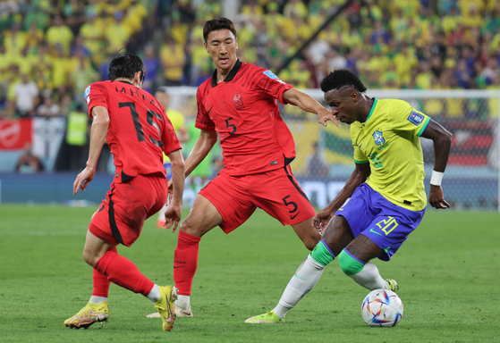 Korea's Jung Woo-young, center, vies for the ball with Brazil's Vinicius Junior during the round of 16 match of the 2022 World Cup at Stadium 974 in Doha, Qatar on Dec. 6, 2022. [NEWS1] 