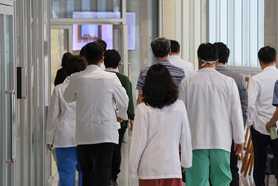 Medical professors at Seoul National University Hospital walk inside a hospital in downtown Seoul after finishing their professorial assembly on Thursday. [YONHAP] 