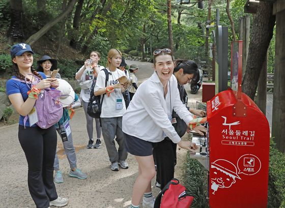 International students from Yonsei University’s Korean Language Institute collect a Seoul Trail stamp as they hike Achasan in eastern Seoul on Thursday. [PARK SANG-MOON]