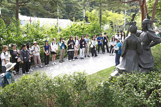 International students from Yonsei University’s Korean Language Institute listen to a tour guide's explanation in front of the statutes of Princess Pyeonggang and the Fool Ondal on Achasan in eastern Seoul on Thursday. [PARK SANG-MOON]