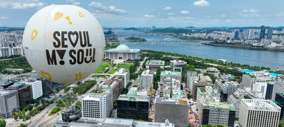 A moon-shaped tethered balloon, floats over Yeouido, western Seoul, on Sunday. It can accommodate up to 30 passengers for rides lasting 15 minutes. [YONHAP]