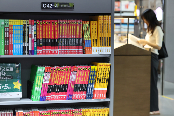 A shopper reads a book near a bookshelf in the job hunting and career section at a bookstore in Seoul on Sunday. [YONHAP]