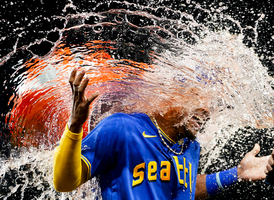 Seattle Mariners center fielder Julio Rodriguez laughs as teammate Teoscar Hernandez douses him as they celebrate a 9-2 win over the Baltimore Orioles in a baseball game on Aug. 11, 2023, in Seattle. This image, by Lindsey Wasson for AP, won the Baseball category at the 2024 World Sports Photography Awards.  [LINDSEY WASSON]