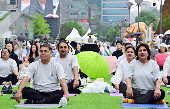 Participants practice yoga during an event celebrating the 10th International Day of Yoga at COEX Plaza in Gangnam District, southern Seoul, on Saturday. [EMBASSY OF INDIA]