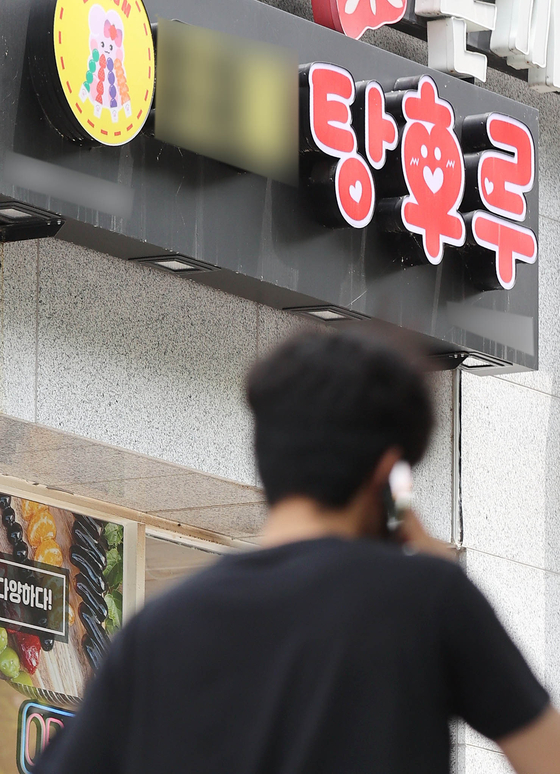 A passenger walks by a store selling tanghulu, or skewered fruit coated in a hardened sugar syrup, in Seoul. [YONHAP]