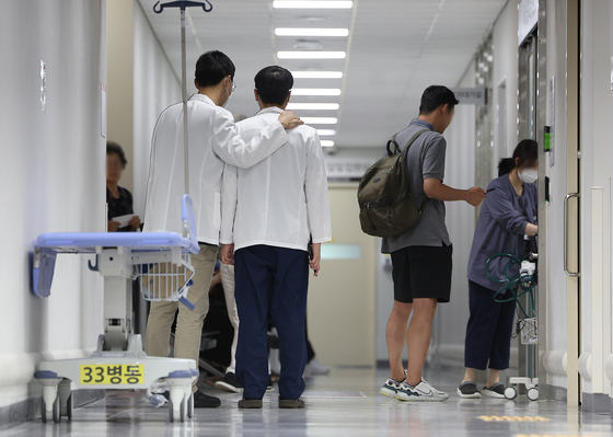 A doctor places his hand on a shoulder of his colleague in a general hospital in Daegu on Tuesday. [YONHAP]