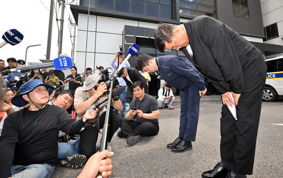 Park Soon-kwan, CEO of Aricell, (right) and other company figures bow their heads at the accident site on Tuesday as they issue a public apology following the massive factory fire that killed 23 workers on Monday. [YONHAP]