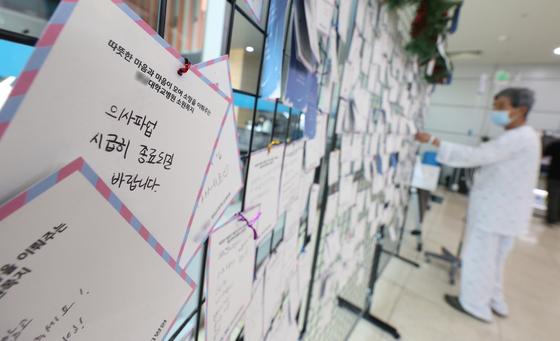 A patient reads handwritten messages to doctors asking them to continue practicing medicine in hospitals rather than going on strike in a general hospital in Daegu on Monday. [YONHAP] 