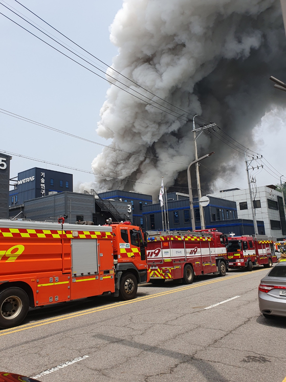 Smoke rise from Aricell, a lithium battery manufacturer in Seosin-myeon, Hwaseong, as fire trucks arrive at the scene. The fire erupted around 10:31 a.m. Monday. [NEWS1]