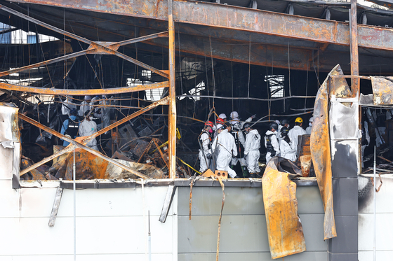 A team of police, firefighters, forensic workers and other government officials conduct a joint investigation at the fire site on Tuesday to determine the cause of the fire. [JOONGANG ILBO]