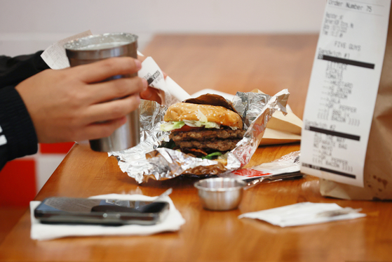 A customer eats a burger at U.S. burger franchise Five Guys' Yeouido branch at The Hyundai Seoul department store in western Seoul. [YONHAP]