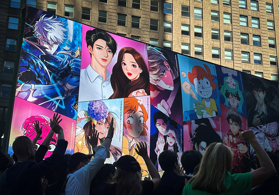 Employees of the digital comics platform Webtoon Entertainment celebrate in Times Square as the company holds an initial public offering (IPO) at the Nasdaq MarketSite in New York on Thursday. [REUTERS/YONHAP]