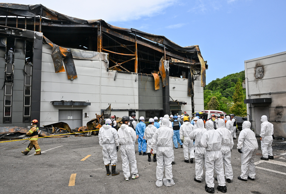 A team of firefighters and forensic workers conduct a joint investigation on Tuesday at a lithium battery plant in Hwaseong, Gyeonggi, where a fire broke out on Monday, resulting in 23 deaths. [YONHAP]