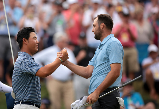 Tom Kim, left, shakes hands with Scottie Scheffler after he went on to win the tournament during a playoff during the final round of the Travelers Championship at TPC River Highlands on June 23 in Cromwell, Connecticut. [GETTY IMAGES]