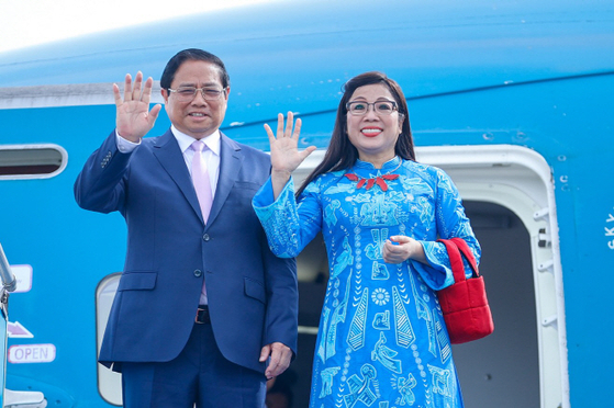 Vietnam's Prime Minister Pham Minh Chinh, left, and his wife wave for the camera before boarding the plane set for Korea at Noi Bai International Airport in Hanoi, Vietnam, on Sunday. [VIETNAM MINISTRY OF FOREIGN AFFAIRS]