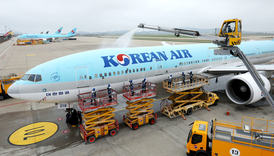 Workers clean Korean Air's Boeing 777-300ER carrier at the airlines' hangar in Incheon International Airport in April. [NEWS1] 